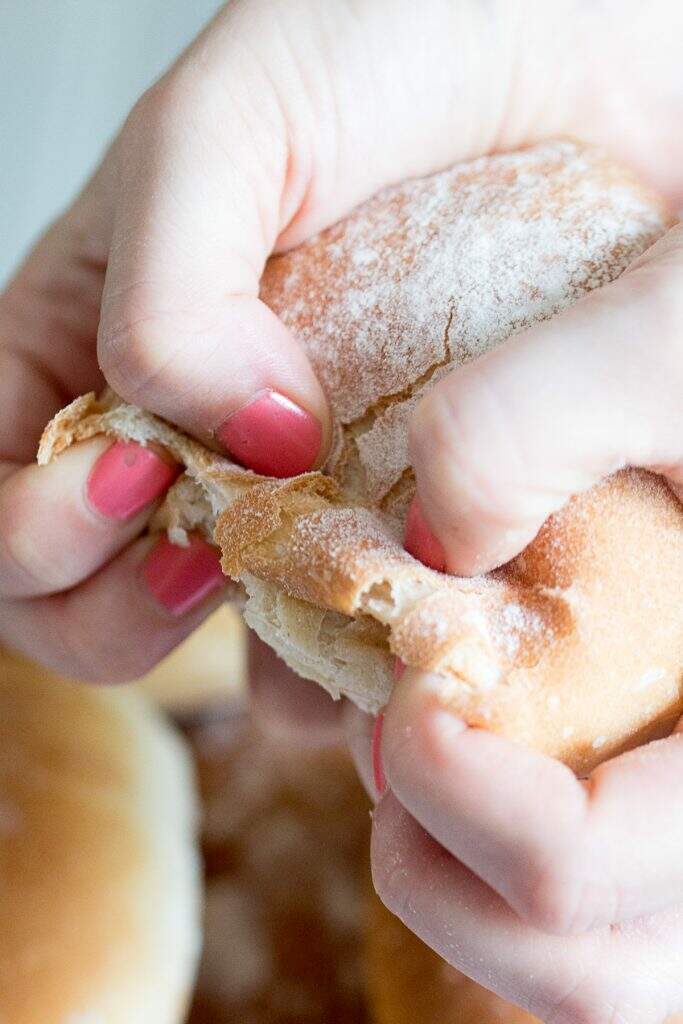 hands pulling apart crusty french bread rolls