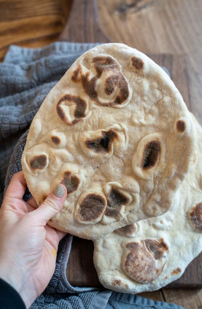 Hand holding homemade naan bread