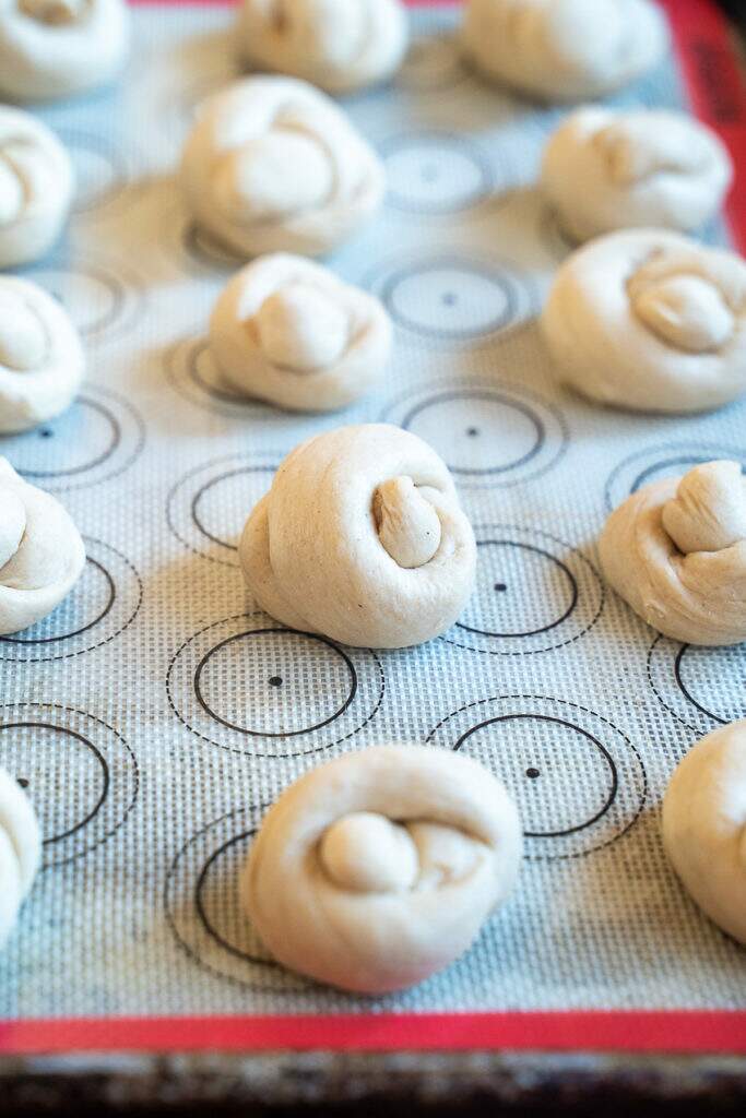 unbaked buttery garlic knots on silicone baking sheet
