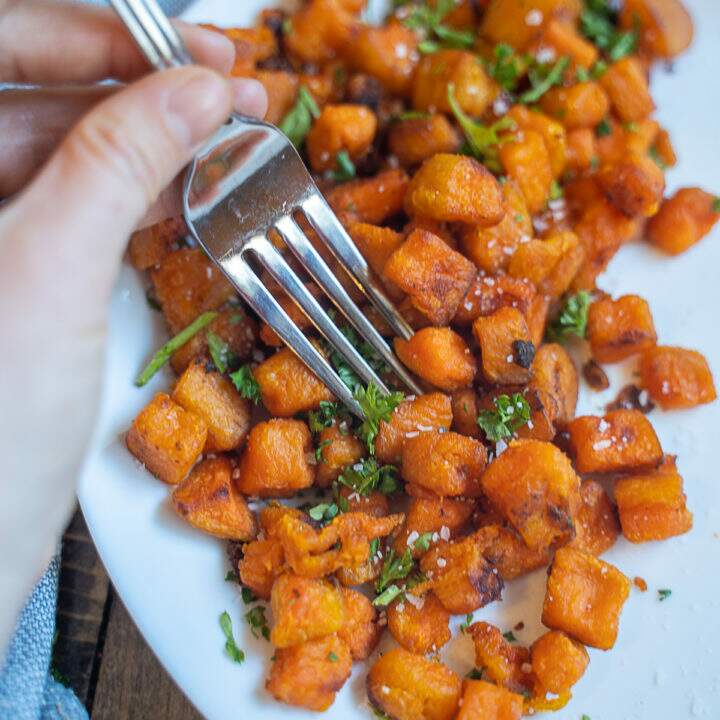 Sweet Potato Home Fries on white plate with hand and fork